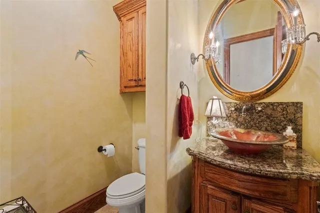 a bathroom with a granite countertop toilet a sink and a mirror