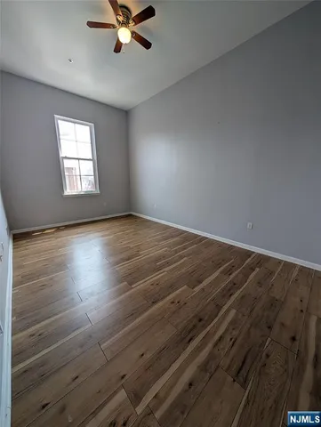 an empty room with wooden floor fan and windows