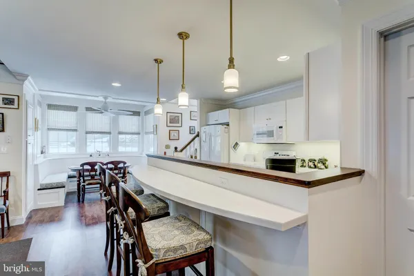 a kitchen with stainless steel appliances kitchen island granite countertop a table chairs stove and white cabinets