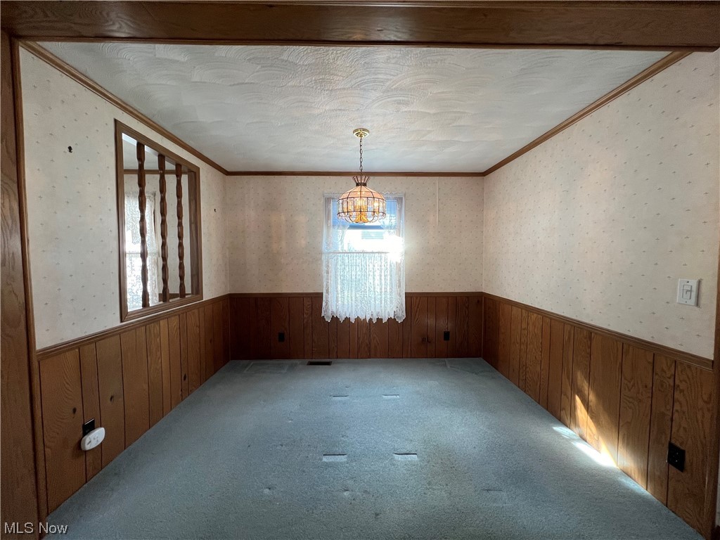 12921 Springfield Road, Unit 3N New Springfield, OH 44443 - Photo 12 of 19 Carpeted spare room featuring a notable chandelier, ornamental molding, and a textured ceiling