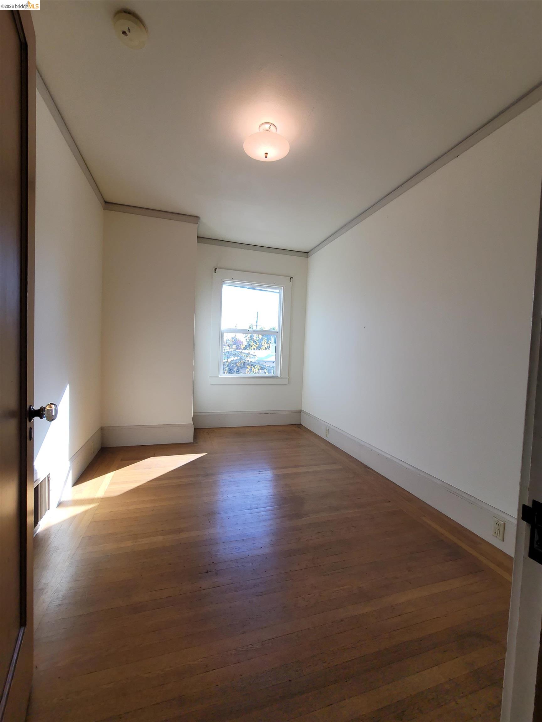 1901 Parker Street, Unit 3 Berkeley, CA 94704 - Photo 14 of 27 an empty room with wooden floor and windows