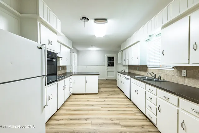 a large white kitchen with granite countertop lots of counter top space and stainless steel appliances