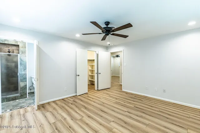 a view of empty room with wooden floor and fan