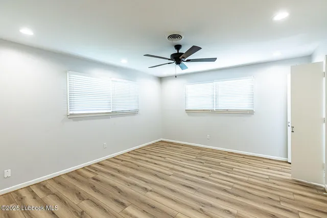 a view of a room with wooden floor and a ceiling fan