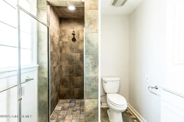 a bathroom with a toilet and a shower