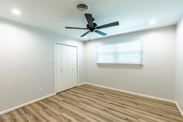 a view of a room with a wooden floor and a ceiling fan