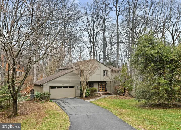 a front view of a house with a yard and large trees