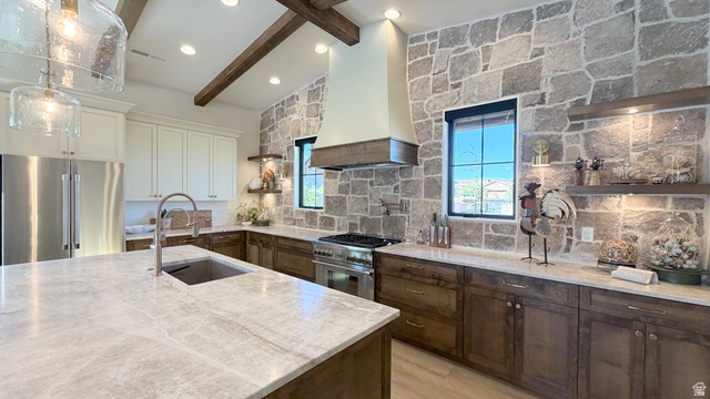 168 South Rancho Santa Fe Virgin, UT 84779 - Photo 17 of 58 Vaulted ceiling with exposed wood beams, stainless steel appliances, stone accent wall, custom range hood, and an oversized kitchen island with an undermount sink