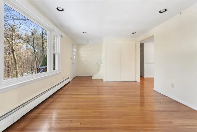 a view of an empty room with wooden floor and a window