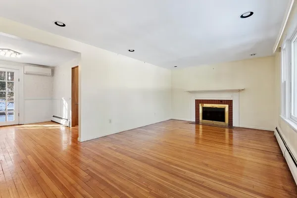 an empty room with wooden floor and fireplace