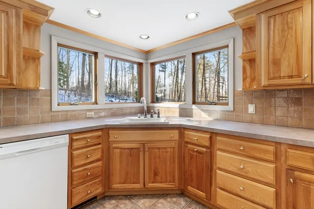 a kitchen with granite countertop wooden cabinets a sink a window and stainless steel appliances