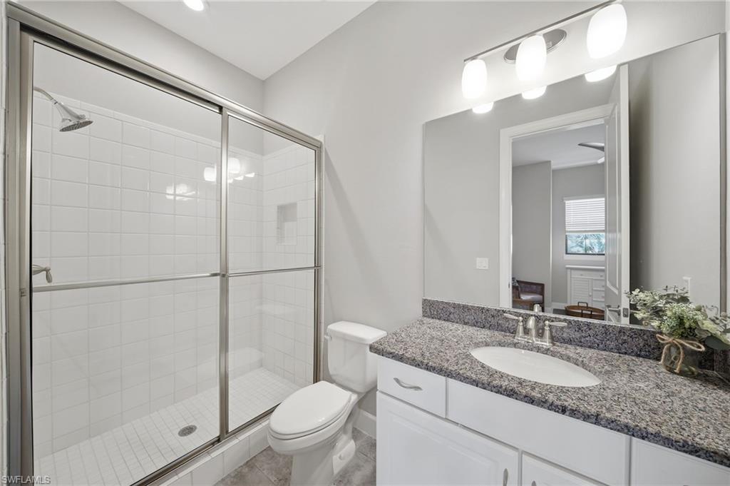 9658 Montelanico Loop, Unit 201 Naples, FL 34119 - Photo 22 of 46 a bathroom with a granite countertop sink toilet and shower