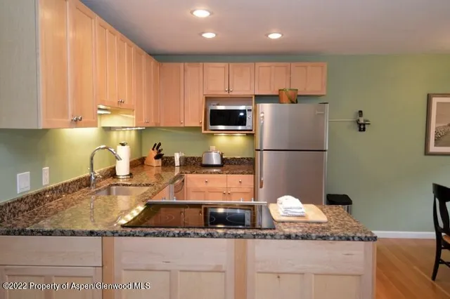 a kitchen with kitchen island granite countertop a sink stainless steel appliances and cabinets