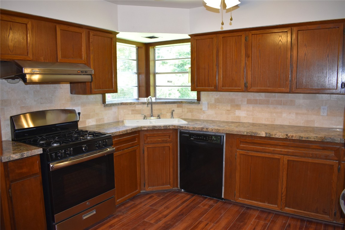 5126 Beechnut Street Houston, TX 77096 - Photo 6 of 20 a kitchen with granite countertop wooden cabinets stove top oven and sink