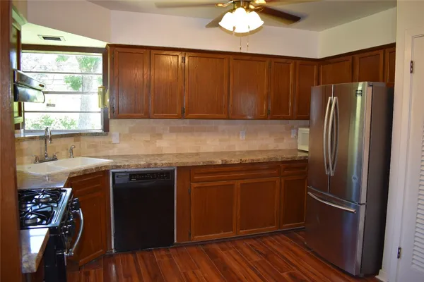 a kitchen with stainless steel appliances granite countertop a refrigerator a sink dishwasher a stove and white countertops with wooden floor