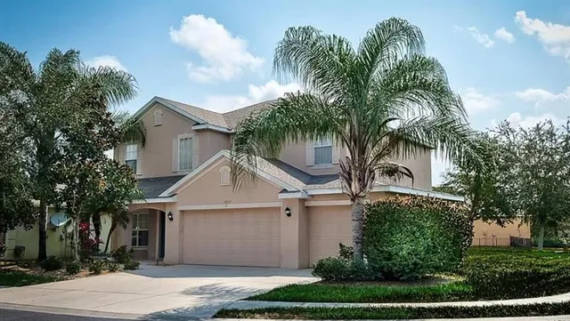 a view of a white house next to a yard with palm trees