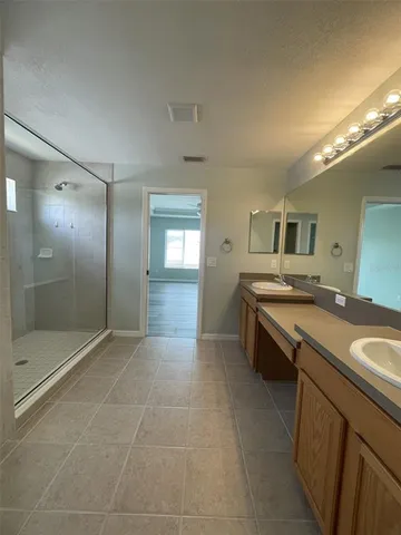 a spacious bathroom with a granite countertop sink a mirror and a shower