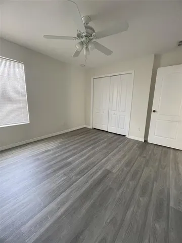 an empty room with wooden floor fan and windows