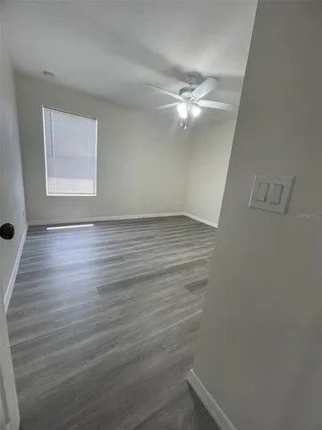 a view of an empty room with wooden floor and a window