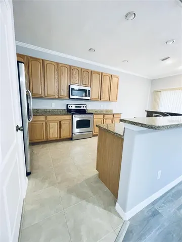 a kitchen with stainless steel appliances granite countertop a stove top oven a sink a refrigerator and white cabinets