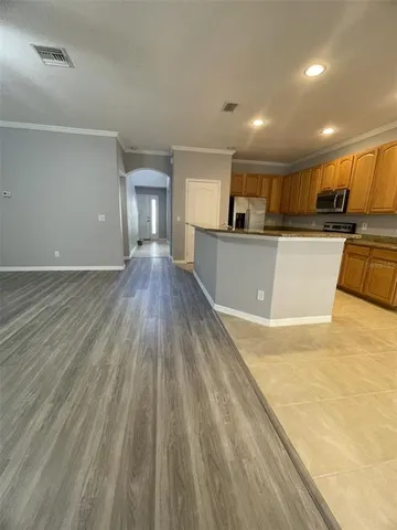 a view of a kitchen with kitchen island a sink wooden floor and a large window