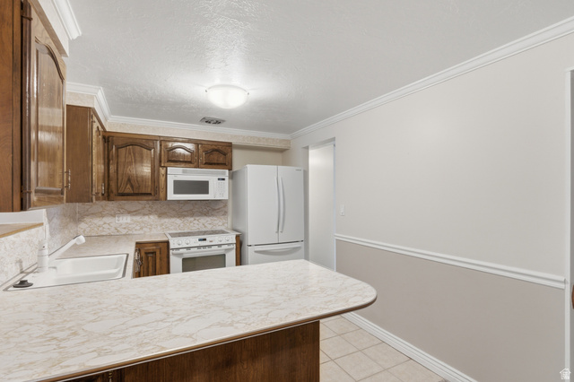 148 Tennyson Avenue Sandy, UT 84070 - Photo 12 of 55 Spacious kitchen featuring a white countertop with a built-in sink, wood-finish cabinetry, and white appliances including a refrigerator, range, and microwave