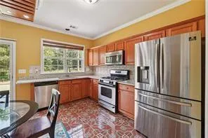 a kitchen with granite countertop a refrigerator stove top oven dining table and chairs