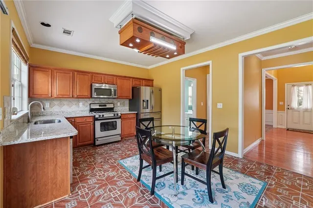 a kitchen with stainless steel appliances granite countertop a stove top oven a sink dishwasher a dining table and chairs with wooden floor