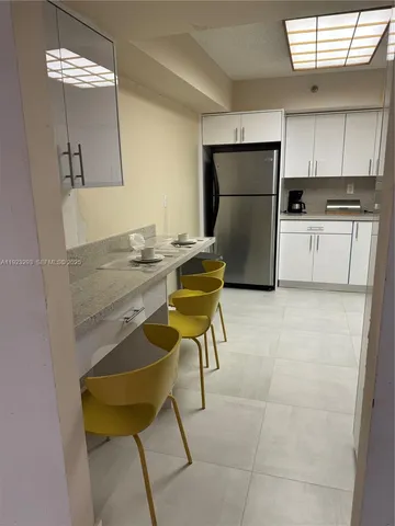 a kitchen with a refrigerator a stove a microwave oven and a dining table with wooden floor