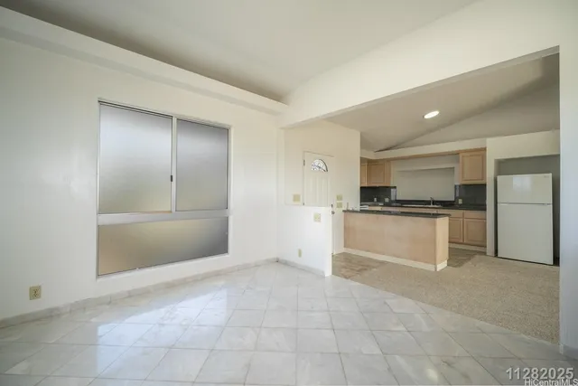 a kitchen with granite countertop a refrigerator and white cabinets