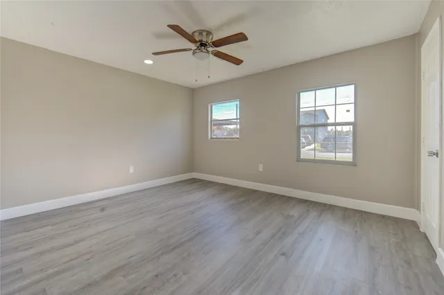 an empty room with wooden floor and windows