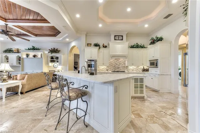 a large kitchen with a lot of white cabinets and stainless steel appliances