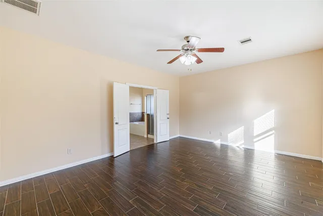 a view of empty room with wooden floor and ceiling fan