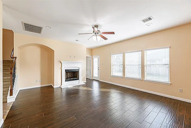 an empty room with windows fireplace and wooden floor