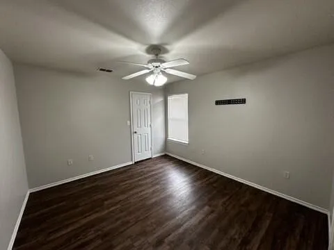 a view of an empty room with window and wooden floor