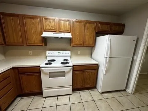 a white refrigerator freezer and a stove sitting inside of a kitchen with granite countertop cabinets