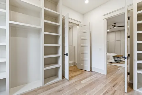 a view of empty room with wooden floor and fan