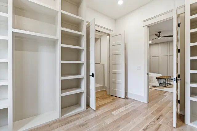 a view of empty room with wooden floor and fan