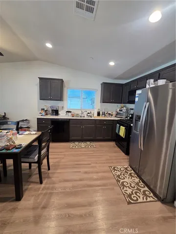 a kitchen with stainless steel appliances a refrigerator a stove a sink a dining table and chairs