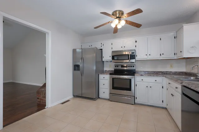 a kitchen with stainless steel appliances a stove a refrigerator a sink a stove with cabinets