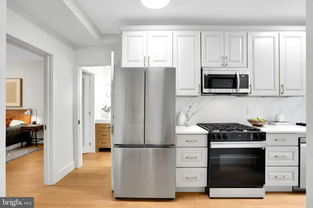 a kitchen with a refrigerator stove and white cabinets