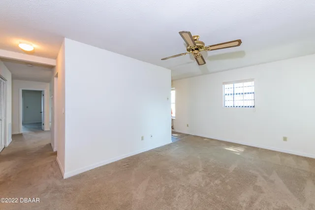 an empty room with windows and fan