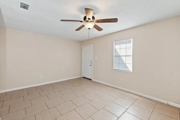 an empty room with windows and fan