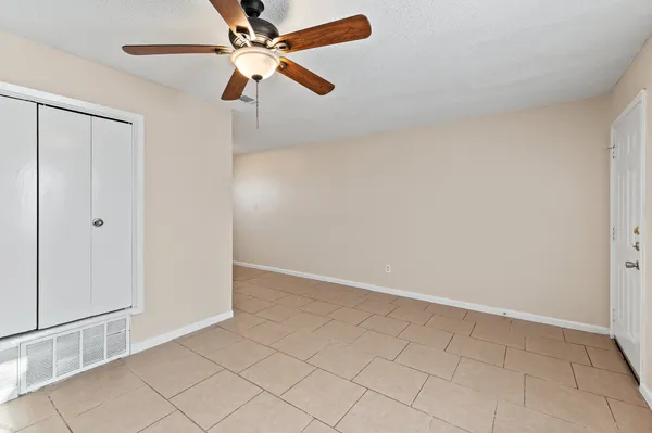 an empty room with a fan & a window