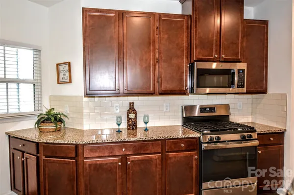 a kitchen with granite countertop a stove a microwave a sink and cabinets