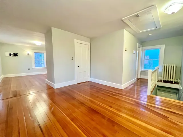 an empty room with wooden floor and a ceiling fan