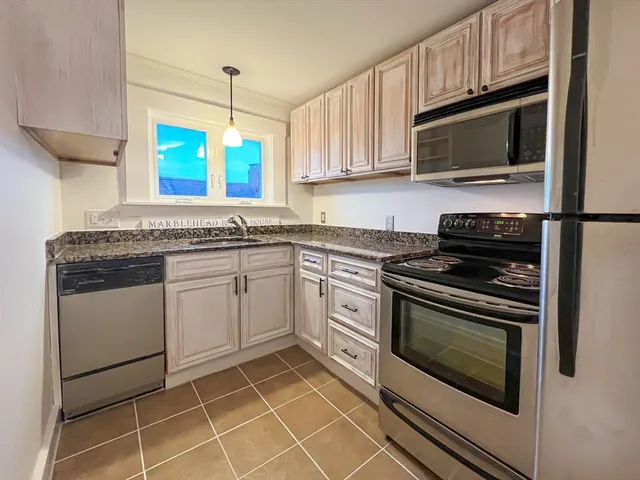 a kitchen with granite countertop a stove top oven microwave and cabinets