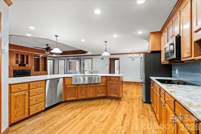 a utility room with stainless steel appliances granite countertop a sink and a refrigerator