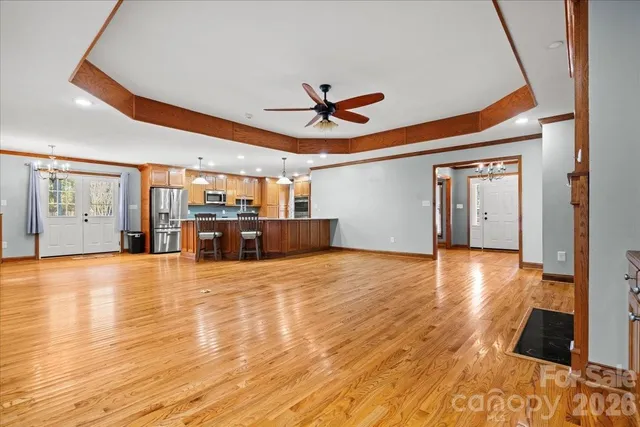 a view of an empty room with window and chandelier fan