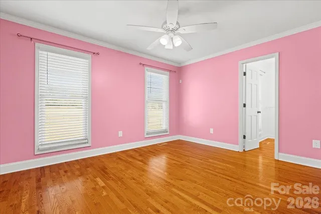 a view of an empty room with window and chandelier fan